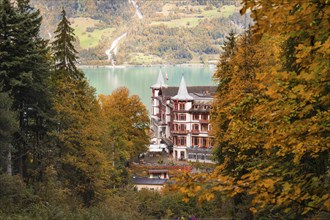 A building on the lake, framed by autumnal trees and mountains, Lake Brienz, Switzerland, Europe