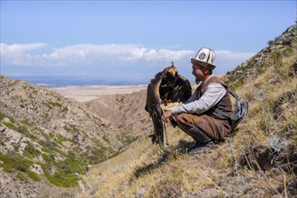 Traditional Kyrgyz eagle hunter with eagle in the mountains, near Kysyl-Suu, Kyrgyzstan, Asia