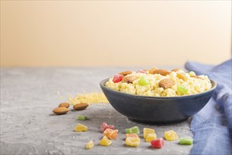 Millet porridge with candied fruits and almonds in blue ceramic bowl on a gray and orange