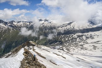 Mountaineer on a rocky ridge with snow, descent from the summit of Schönbichler Horn, view of