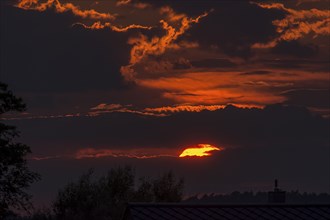 Red sun behind clouds in the evening sky, Mecklenburg-Vorpommern, Germany, Europe