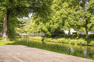 A bridge spans a river, surrounded by green trees and summer nature, Nagold, Black Forest, Germany,