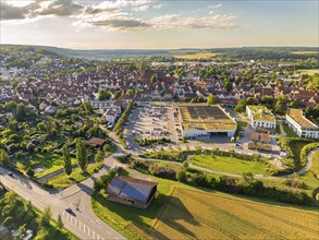 Aerial view of a city outskirts with a large shopping centre, car parks and surrounding landscape,