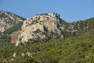 An old stone castle perched on a rocky cliff with forests in the background, Kastro Monolithou,