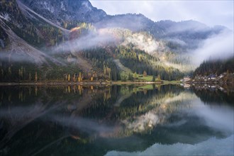 The Vordere Gosausee in autumn with a view of the Gasthof Gosausee. Sun and clouds. Overcast.