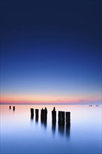 Stone pyramids on old groynes with algae in the water on the beach of the Baltic Sea, long exposure