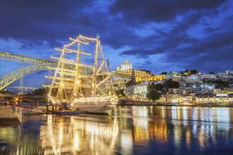 View of Vila Nova de Gaia city with a sailing ship and Dom Luis I bridge over Douro river in the