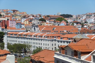 Panoramic view of a historic city with red tiled roofs and colourful houses under a blue sky,