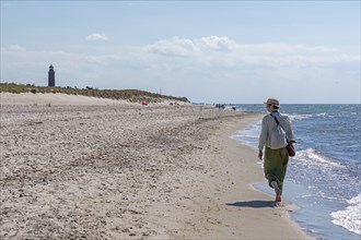 Elderly woman walking on the beach, lighthouse, Darßer Ort, Born a. Darß, Mecklenburg-Vorpommern,