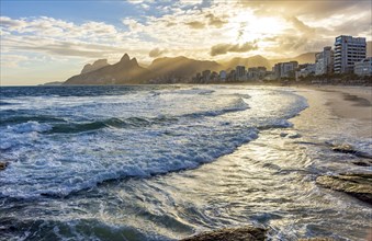 Sunset on Ipanema beach in Rio de Janeiro with its buildings in front and mountains in the