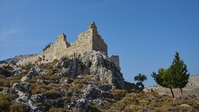 Ruin of an old tower on a rocky hill under a blue sky, Archengelos village, Rhodes, Dodecanese,