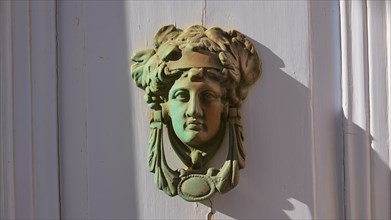 An antique bronze door knocker in the shape of a head, decorative and classically designed, Chora,