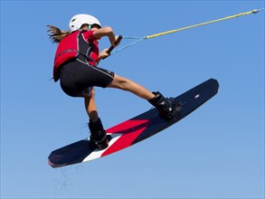 Boy or girl, jump over jump with wakeboard, red life jacket and water sports, water skiing in the