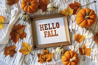 Top view of cozy autumn arrangement with picture frame with text 'Hell fall', pumpkins and colorful