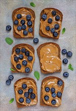 Rye bread with peanut paste and fresh blueberries, top view, no people