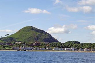 Coastal town with houses and a green hill in the background by the sea, North Berwick, Scotland,