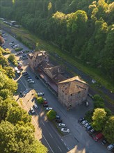 Aerial view of an old railway station building next to a street with many parked cars, surrounded