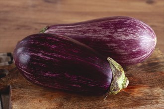 Purple and white eggplant, on a wooden chopping board, top view, raw eggplant, no people