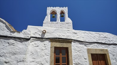 White building with bell tower and windows in front of a bright blue sky, Chora, Old Town, Patmos,