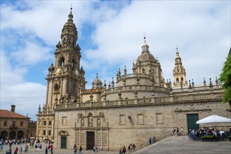 Historic cathedral in baroque style with towers against a blue sky and people in the square,