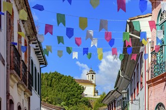 Street decorated with flags for the Saint John festivities with colonial-style houses and a church