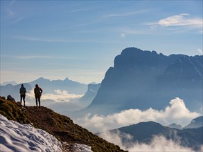 Two mountaineers with a view of Sassolungo, clouds in the valley, Sciliar, Dolomites, South Tyrol,