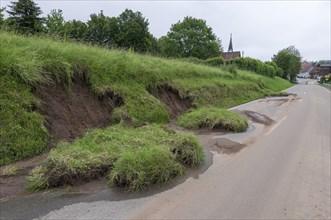 Symbolic image of climate change, slippery slope on a country road after heavy rainfall, near