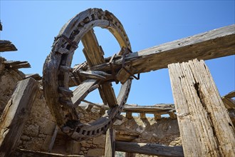 Close-up of a wooden cogwheel and wooden beams in an abandoned old mill under a clear sky,