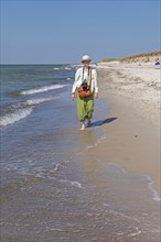 Elderly woman walking barefoot on the beach, Darßer Ort, Born a. Darß, Mecklenburg-Vorpommern,