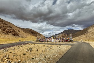 Road and Buddhist prayer flags (lungta) at Namshang La pass in Himalayas. Ladakh, India, Asia