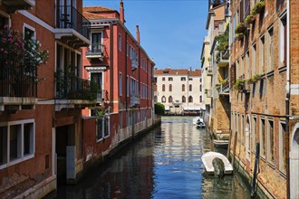 Narrow canal between colorful old houses with gondola boat in Venice, Italy, Europe