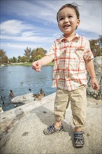 Young chinese and caucasian boy having fun at the park and duck pond