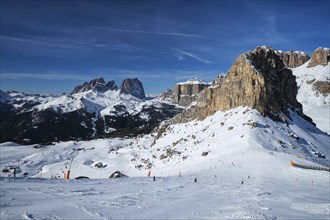 View of a ski resort piste with people skiing in Dolomites in Italy. Ski area Belvedere. Canazei,