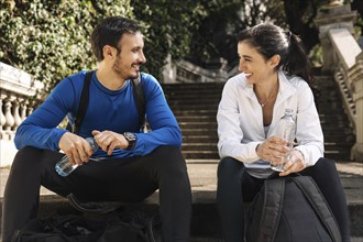 Man and woman resting together after jogging sitting on the steps of a park