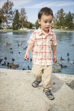 Young chinese and caucasian boy having fun at the park and duck pond