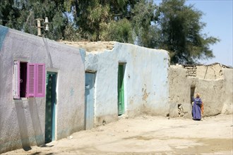 Bedouin woman in street with traditional houses in the Farafra Oasis in the Western Desert, Egypt,