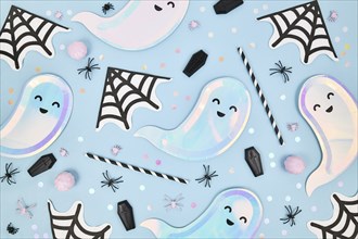 Cute pastel colored Halloween party flat lay with ghost shaped plates, spider web napkins and