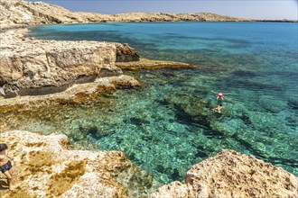 Tourists bathing in the crystal-clear turquoise waters of the Cape Greco peninsula, Agia Napa,