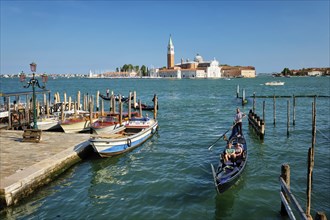 VENICE, ITALY, JULY 19, 2019: Gondolier with tourists in gondola in lagoon of Venice by Saint Mark