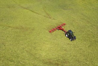 Drone view of a tractor turning hay in the field, Flachgau, Land Salzurg, Austria, Europe