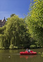 Father and son in a pedal boat on the river Lahn with the Old University in the background,