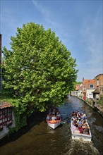 BRUGES, BELGIUM, MAY 28, 2018: Tourist boats with tourists in canal between old houses. Brugge