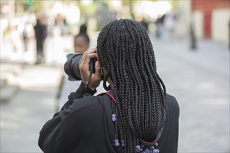 Young girl with black dreadlocks taking a photo, Paris, France, Europe