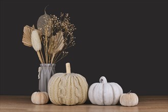 Fall decoration with boho style knitted beige pumpkin and gray stone pumpkin on dark backgroun