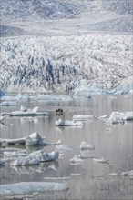 Boats with tourists in the glacier lagoon, ice lagoon Fjallsárlón, ice floes in front of glacier