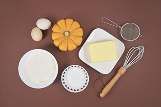 Pumpkin pie ingredients and baking tools on brown background