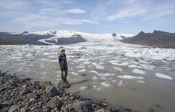 Tourist at glacier lagoon, peak Sveinstindur, ice lagoon Fjallsárlón, ice floes in front of glacier