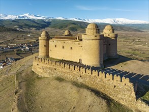 The Renaissance castle of La Calahorra against the snow-capped Sierra Nevada mountain range, aerial