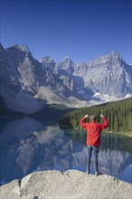 Tourist with open arms on look-out point looking over Moraine Lake in the Valley of the Ten Peaks,