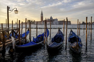 Venetian gondolas near St. Mark's Square in the morning light, in the background the monastery of